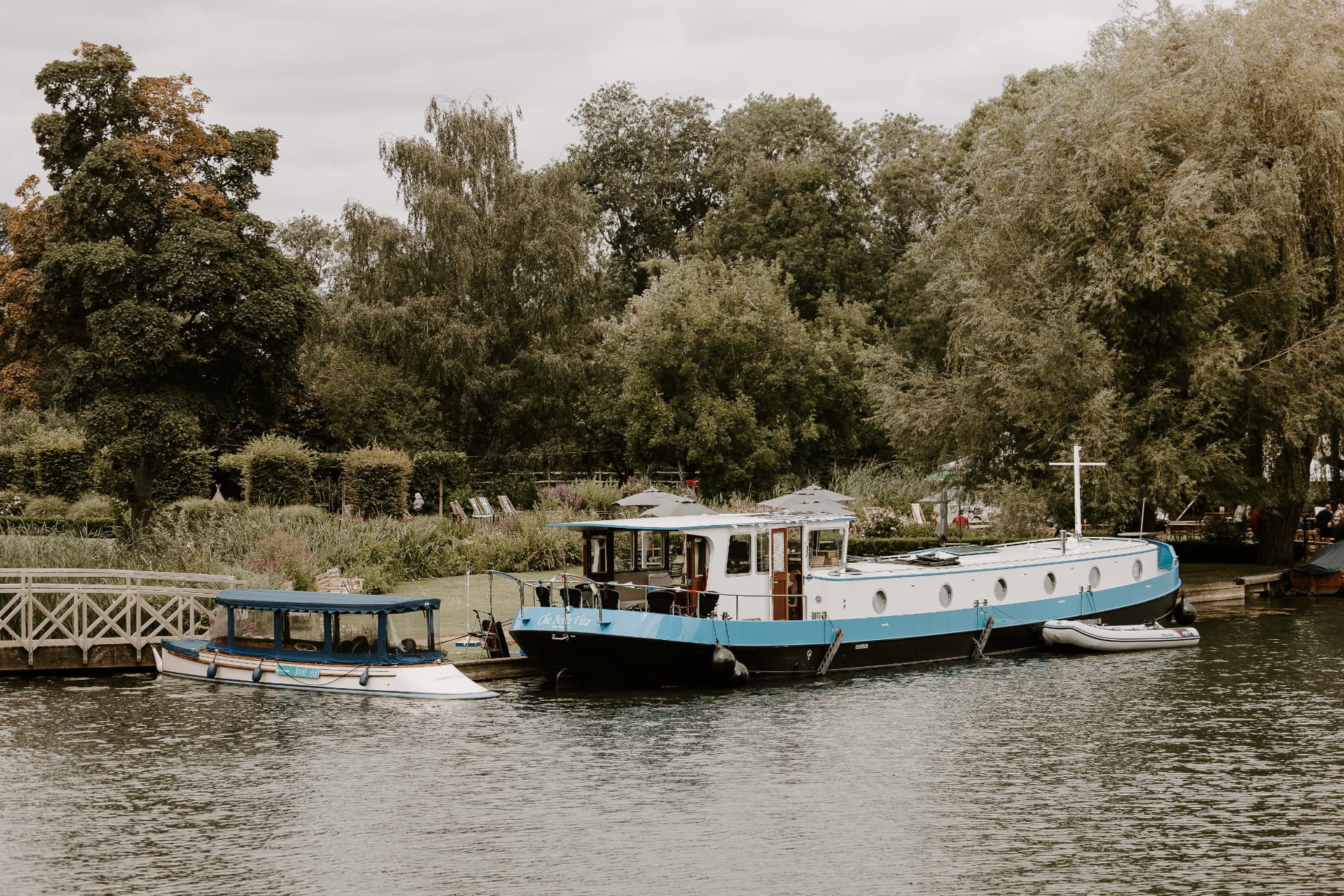Che Bella Vita moored beside a tree-lined bank with her tender alongside