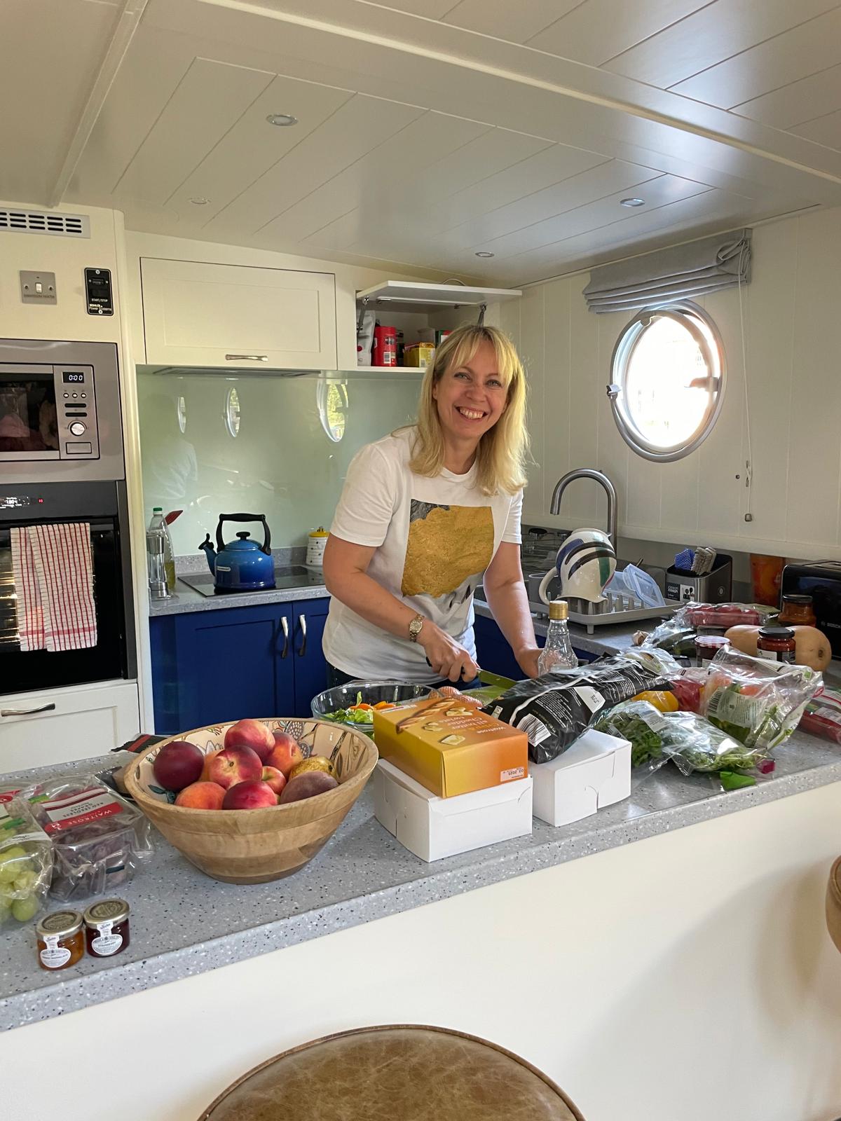 Kate smiling in the galley, knife in hand among the day's provisions