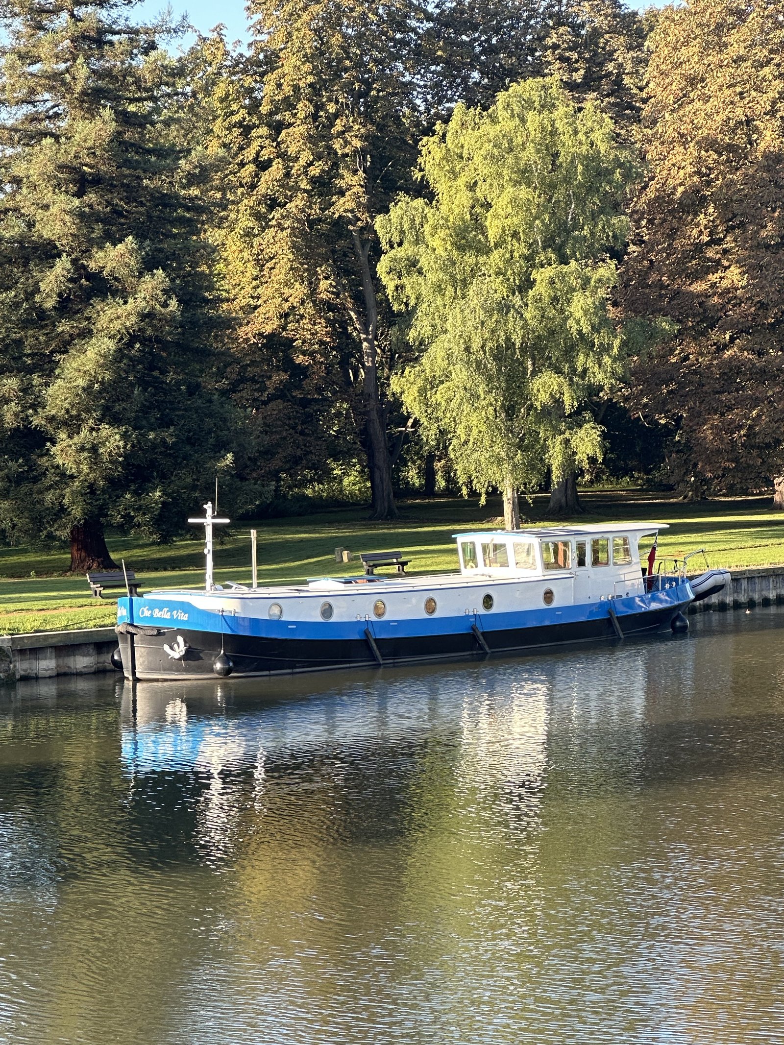 Che Bella Vita moored on a river beneath autumn trees